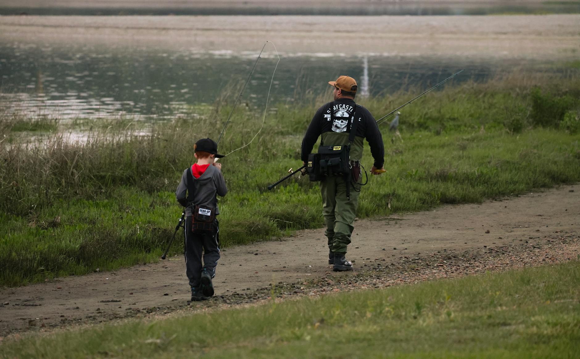 man and boy walking next to lake